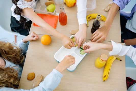 arms reaching over table with fruits and vegetables