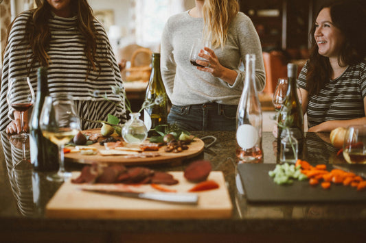 two women standing beside woman sitting in front of table