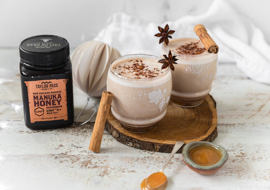 two cups of eggnog with a jar of honey