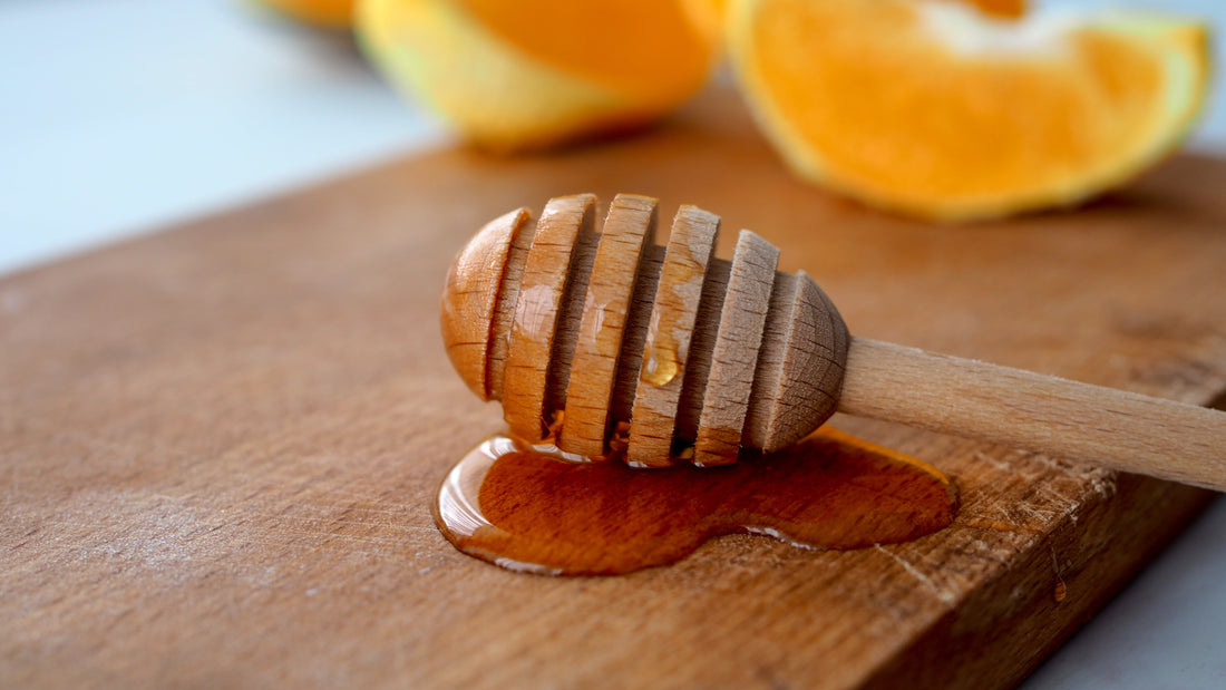 honey dipper dripping on brown cutting board orange slices