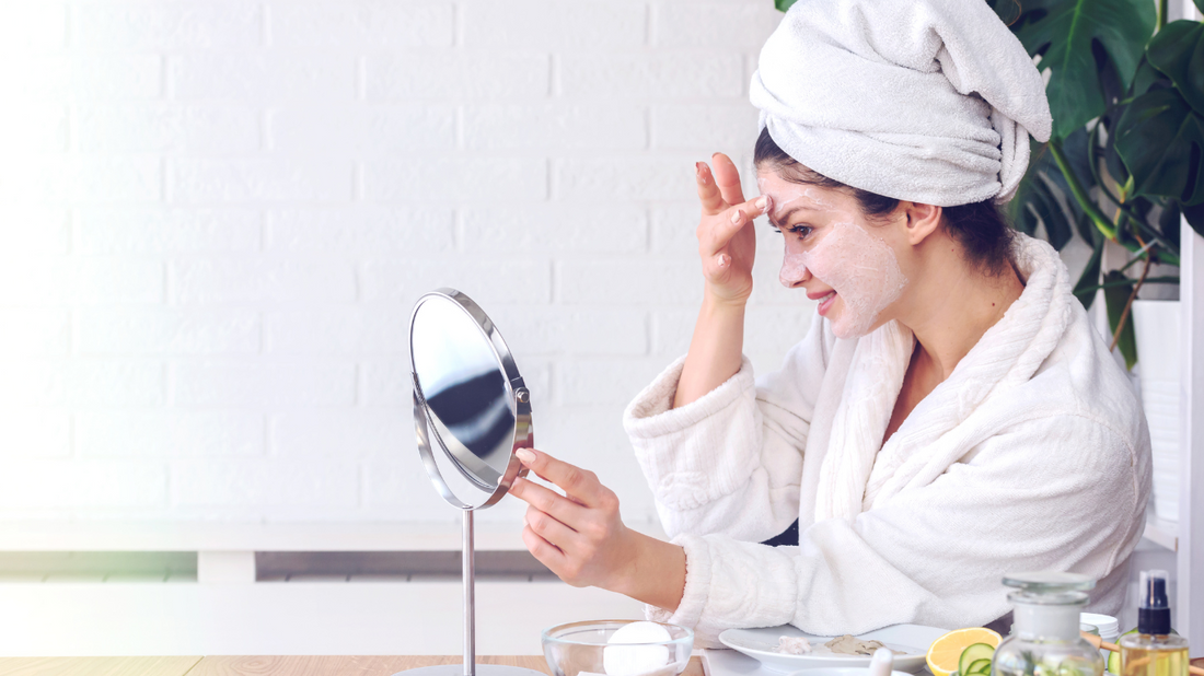 skincare routine woman with white towel and robe looking in mirror