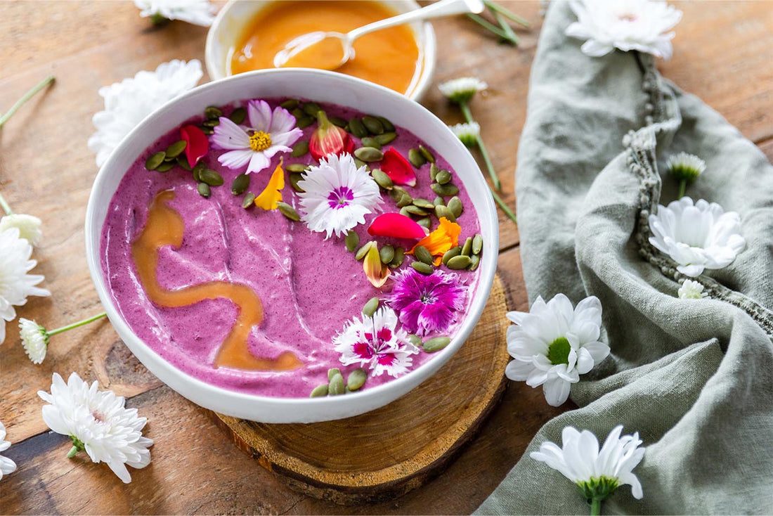 Bowl with pink smoothie inside and flowers on top